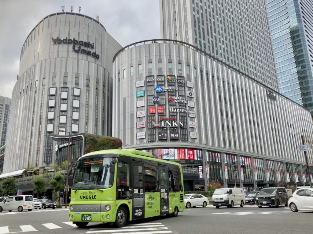 年末年始も営業するリンクス梅田の建物と梅田エリアを走る循環バス(うめぐるバス)が写っている写真